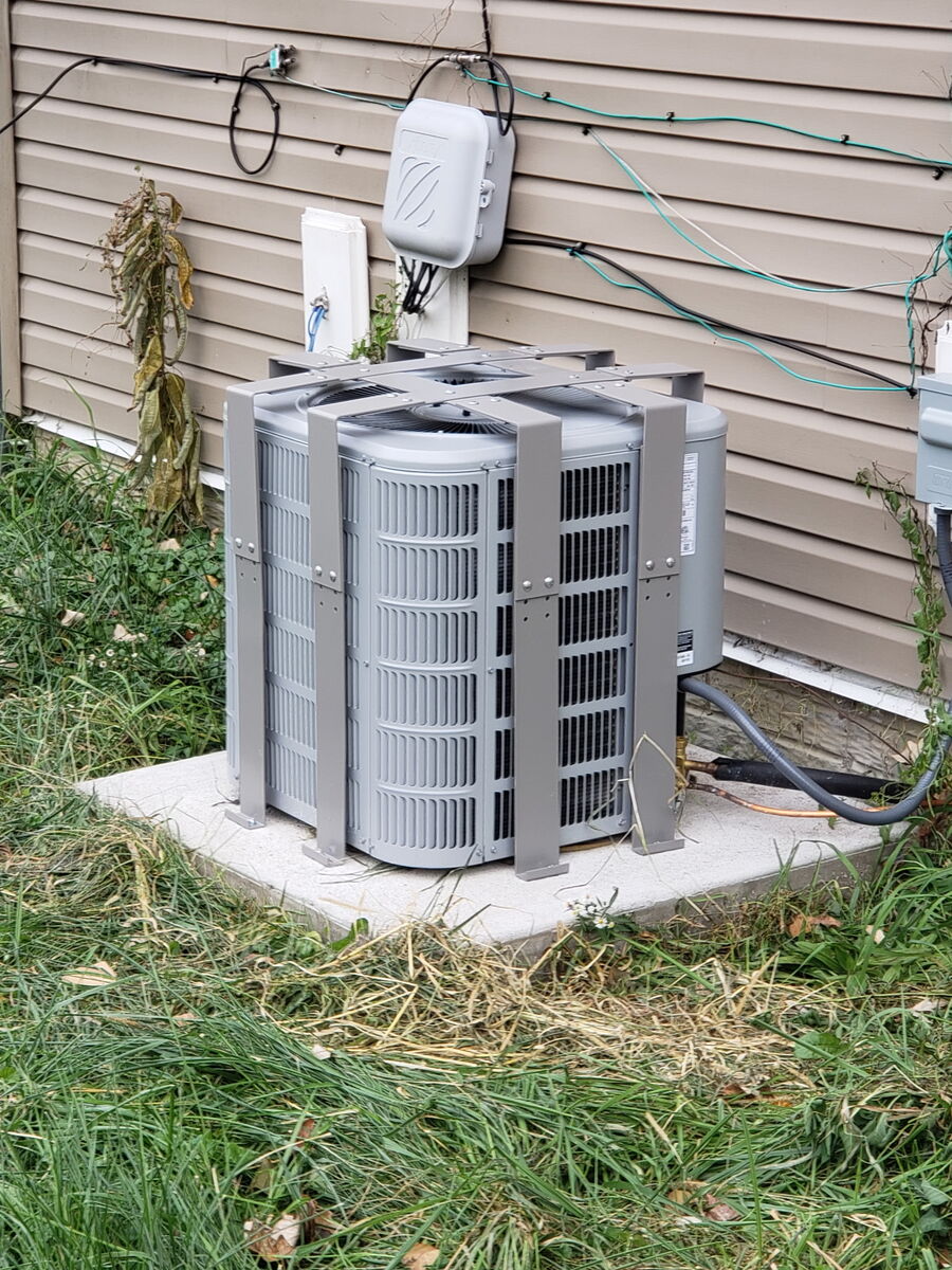 AC Bandit cage secured over a residential AC condenser next to a chain-link fence